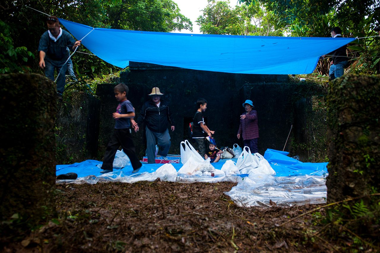 An Okinawan family prepares to pray and offer food to their ancestors for the annual Shimi celebration in 2016, at Kadena Air Base in Japan. Since before World War II, tombs have been located on what is now the base.