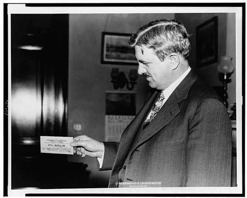 Senator Clarence Dill holds a piece of Tenino's wooden money.