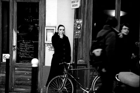 A woman smoking outside a cafe in Paris.
