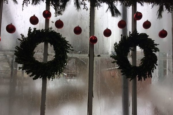Evergreen wreaths hang from foggy windows.