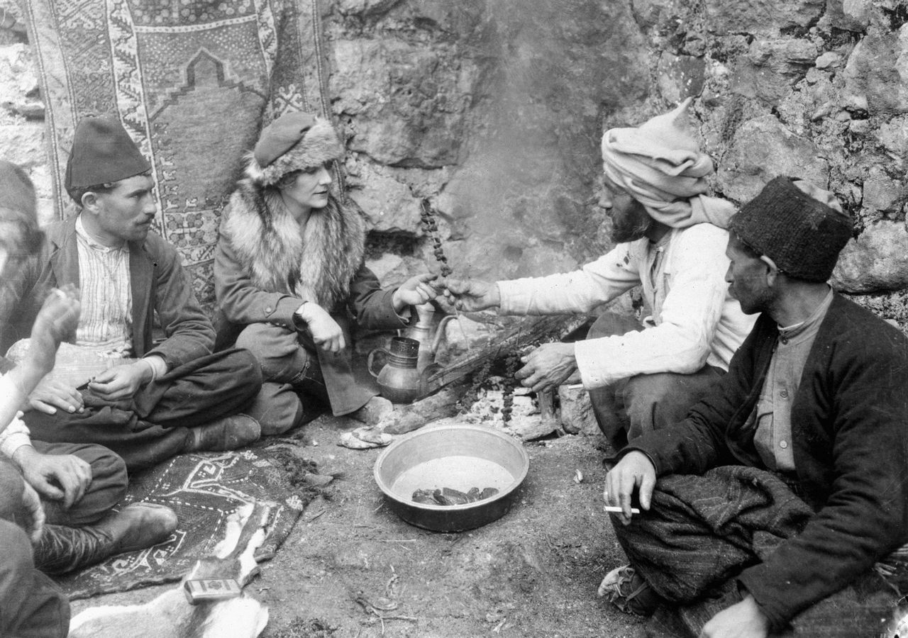 Journalist and explorer Marguerite Harrison shares a meal with a group of Bakhtiari men. (From the documentary <em>A Nation's Battle for Life</em> by Merian Cooper and Ernest Schoedsack)