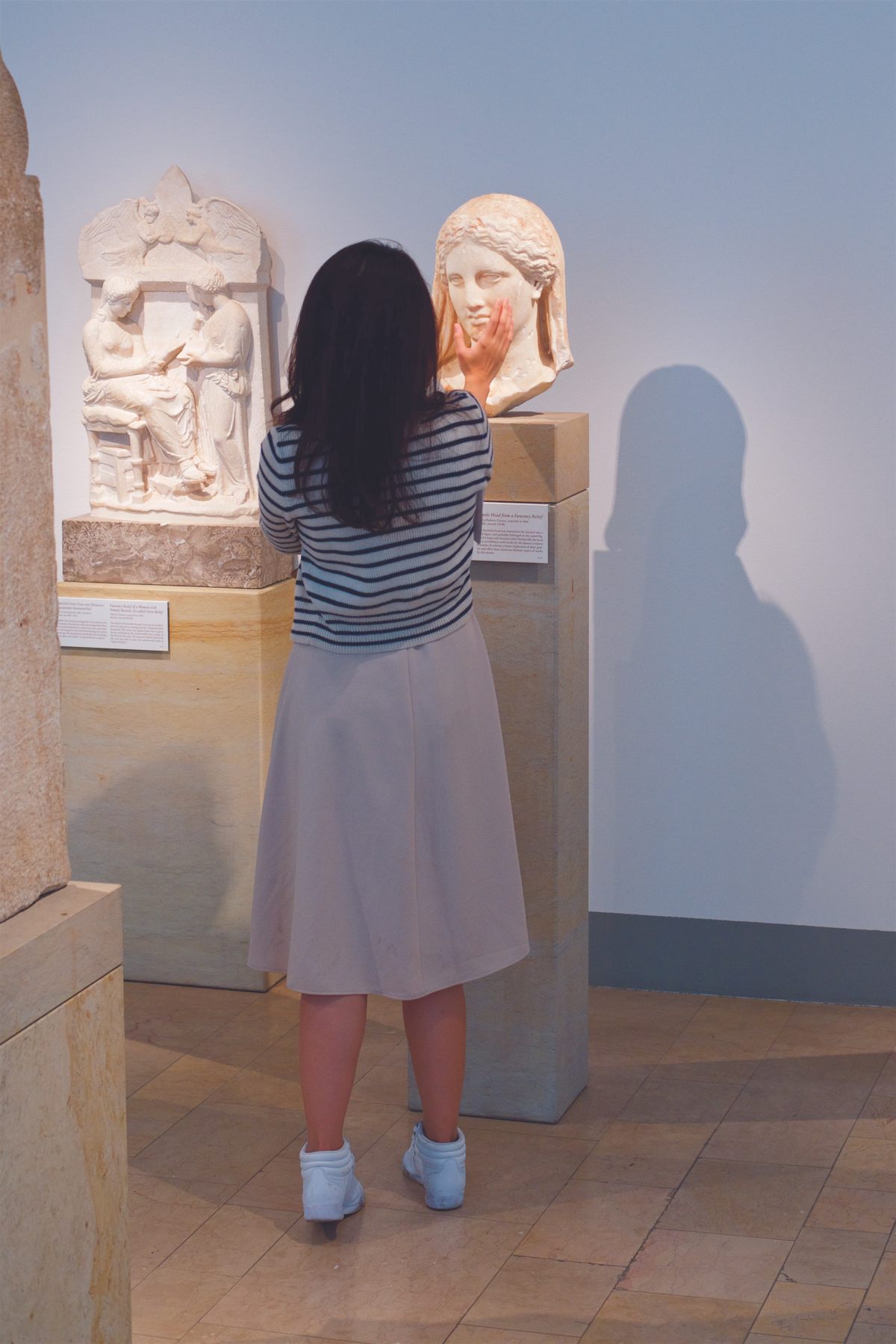 A visitor cuts the face of a bust at the Altes Museum in Berlin.