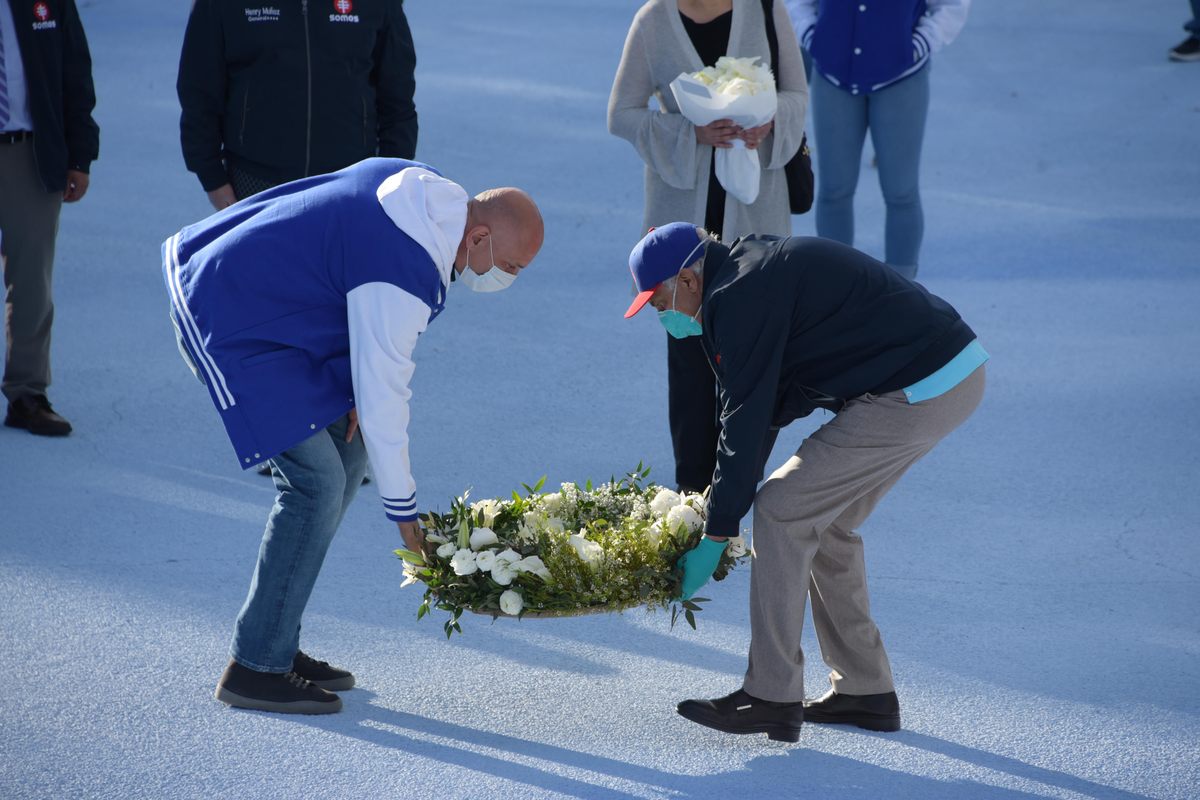 The artist, Jorge Rodríguez-Gerada (left), and doctor and chairman of SOMOS Community Care, Ramon Tallaj, lay a wreath in honor of Decoo.
