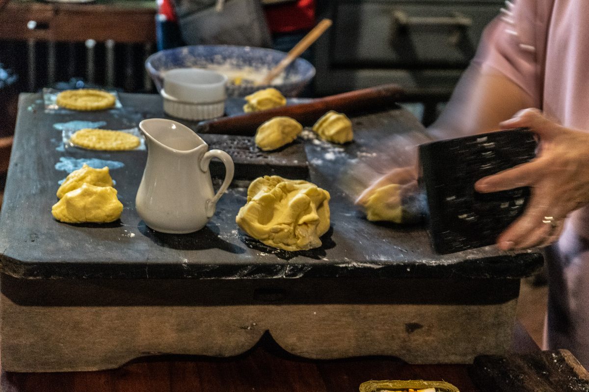 Atching Lillian works her egg yolk-y dough on an antique mold to imprint the face of Saint Nicholas, patron saint of bakers.