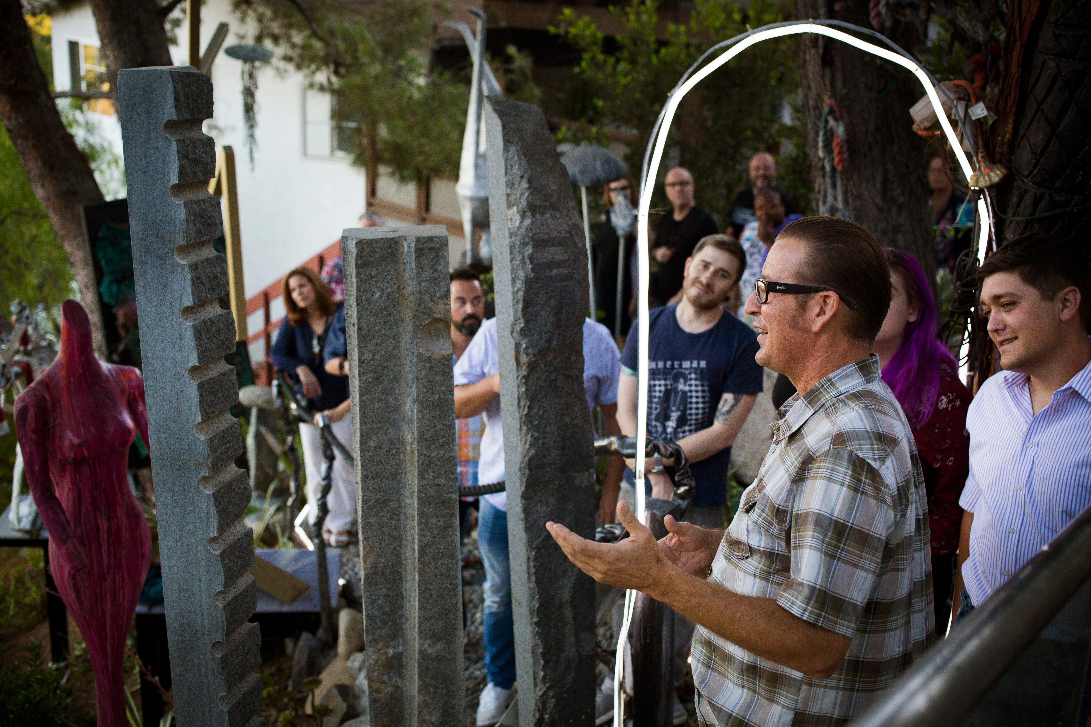 An artist with work in the sculpture garden chats with guests.
