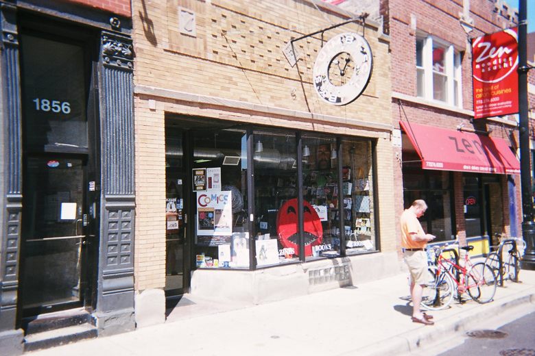 The brick storefront of Quimby's Bookstore in Chicago features large windows filled with comics and zines.