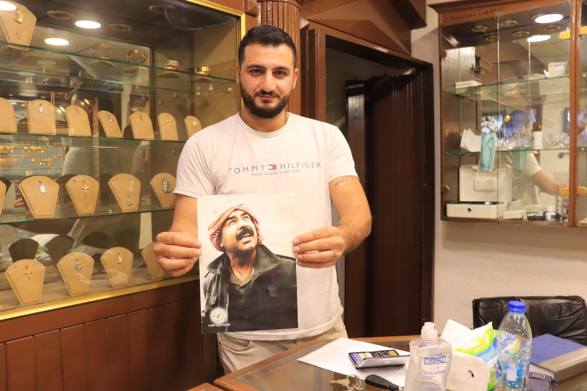 Adeeb holds up a photograph of Saddam inside his gold shop.