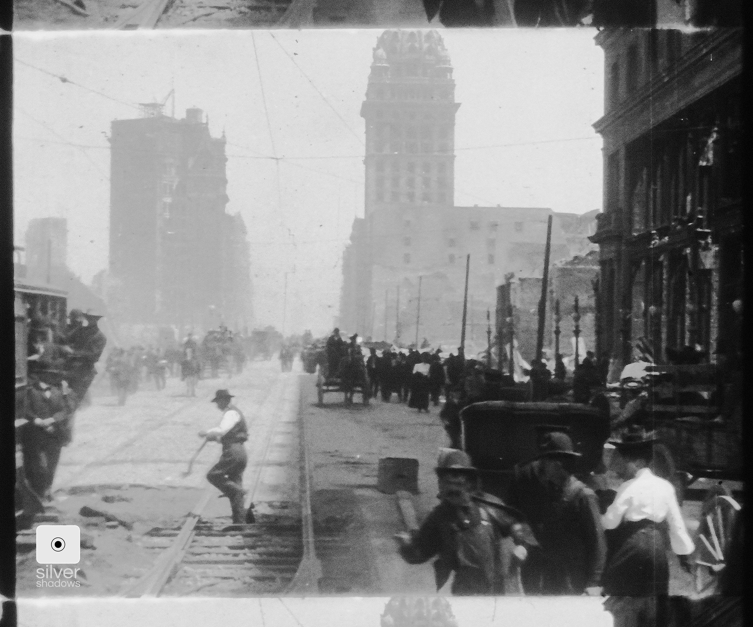 A street car drives down Market street passing people walking.