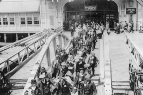 Immigrants walking across the pier at Ellis Island, early 20th century. 