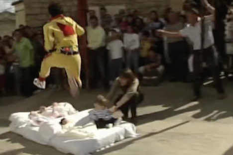 Watch Men Dressed as Devils Jump Over Babies