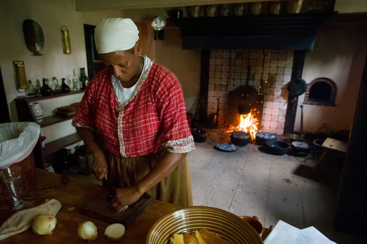 Lavada Nahon cooking a historical dinner using a jambless fireplace, a Dutch-style hearth prominent in the 17th century.