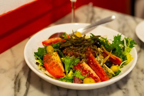 omàtiga de aregada is a salad of bitter escarole topped with a mix of minced tomatoes, salted sardines and pickled sea fennel.