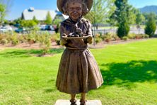 The bronze statue of Little Debbie depicts the character holding a tray of Swiss Rolls.