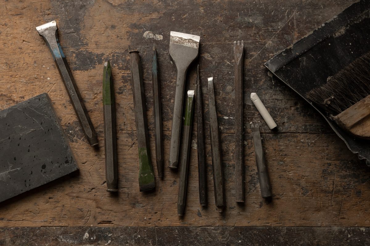 A carver uses different tools to form letters and intricate designs depending on the type of stone.