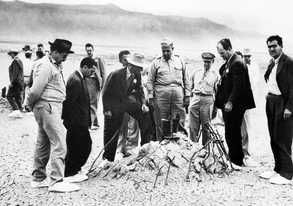 J. Robert Oppenheimer (in the hat) stands on the remains of the test site tower during a September 1945 press conference.