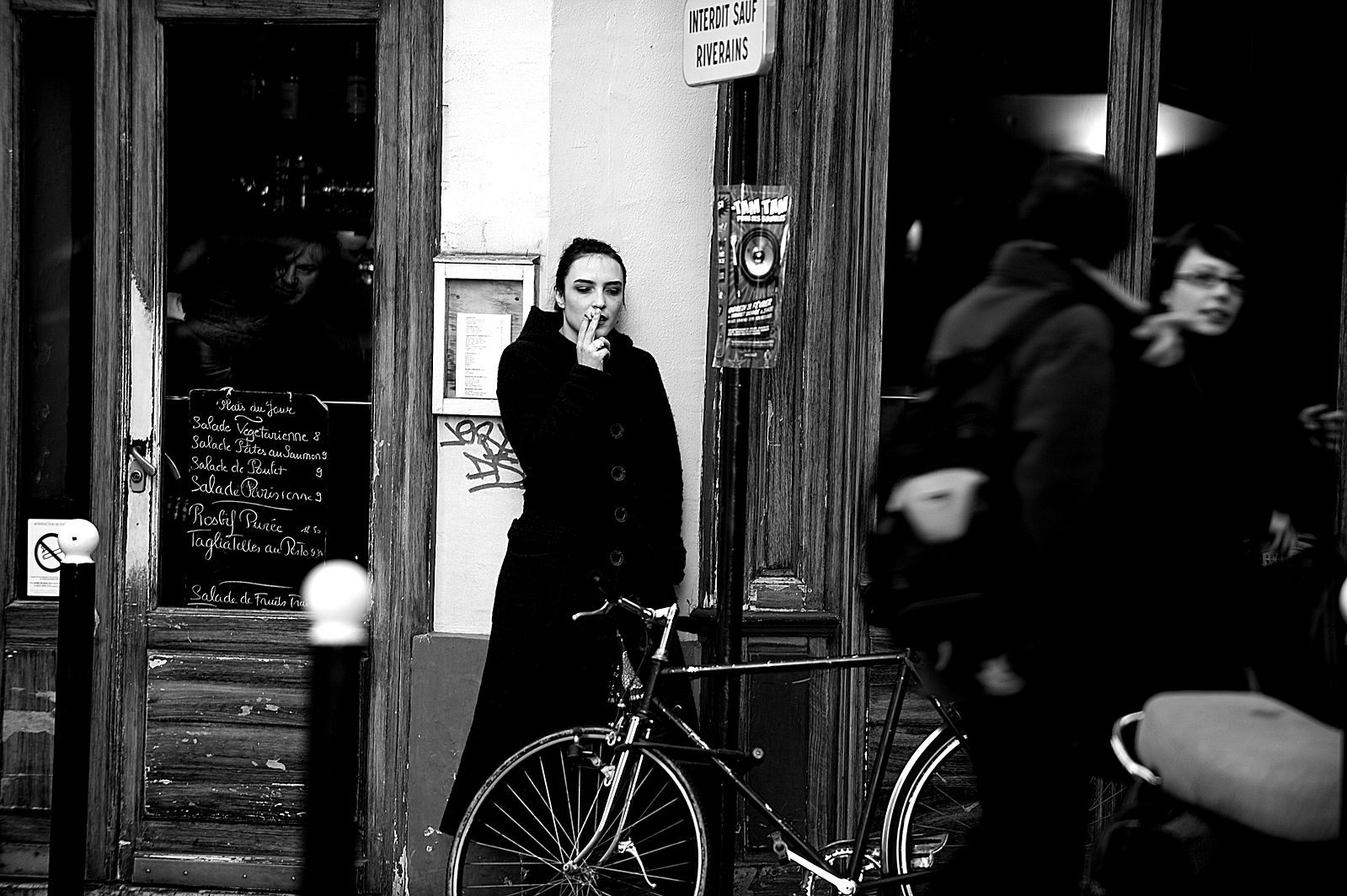 A woman smoking outside a cafe in Paris.