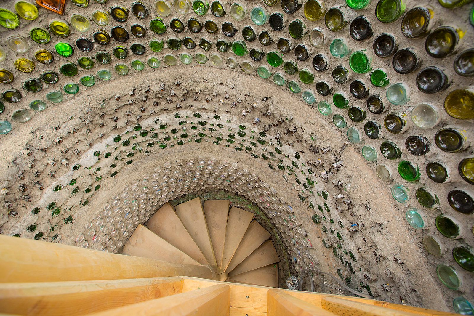 An intricate mosaic wall of bottles in a two-story Earthship.