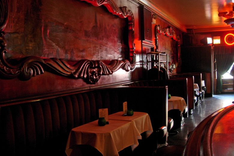 Dimly lit booths at the Green Mill Jazz Club with ornate wood carvings and red lighting over white tablecloths.