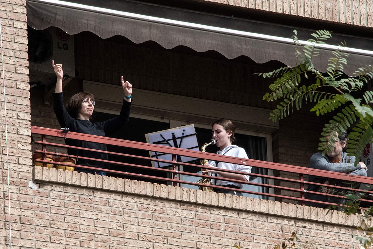 A woman plays the saxophone from her balcony during home confinement in Valencia, Spain. Music can make the social distance seem smaller.