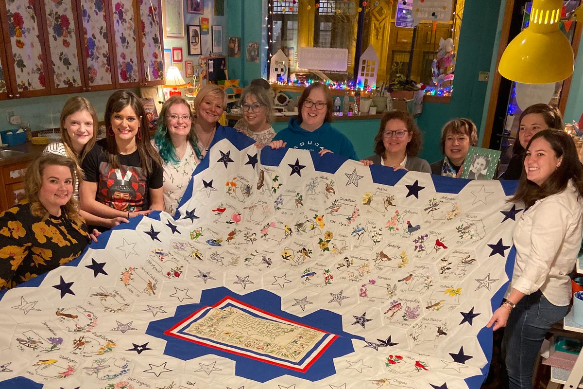 The completed quilt, surrounded by some of the volunteers who worked on it.