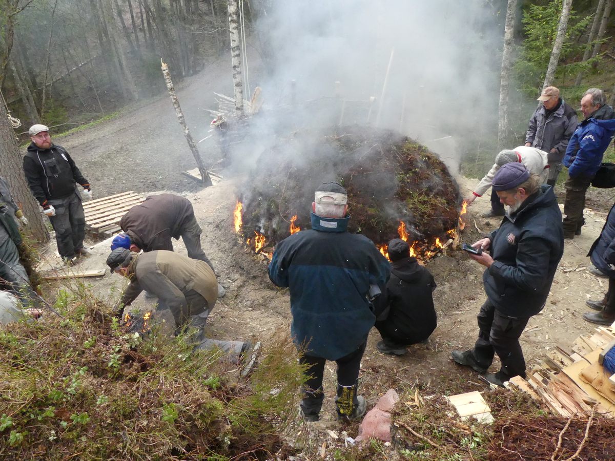 The wood mound is covered by layers of cut peat. The fire, which can burn for up to three days, releases tar that is collected below.