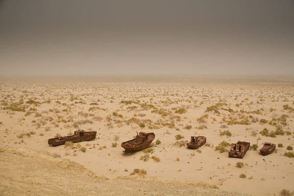 A rusted fleet sits crumbling in the sunbaked desert