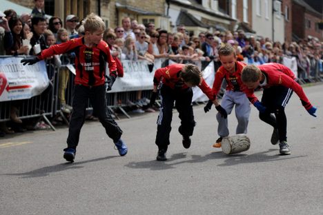A team of children wheel a block of wood down the street in Stilton, England.