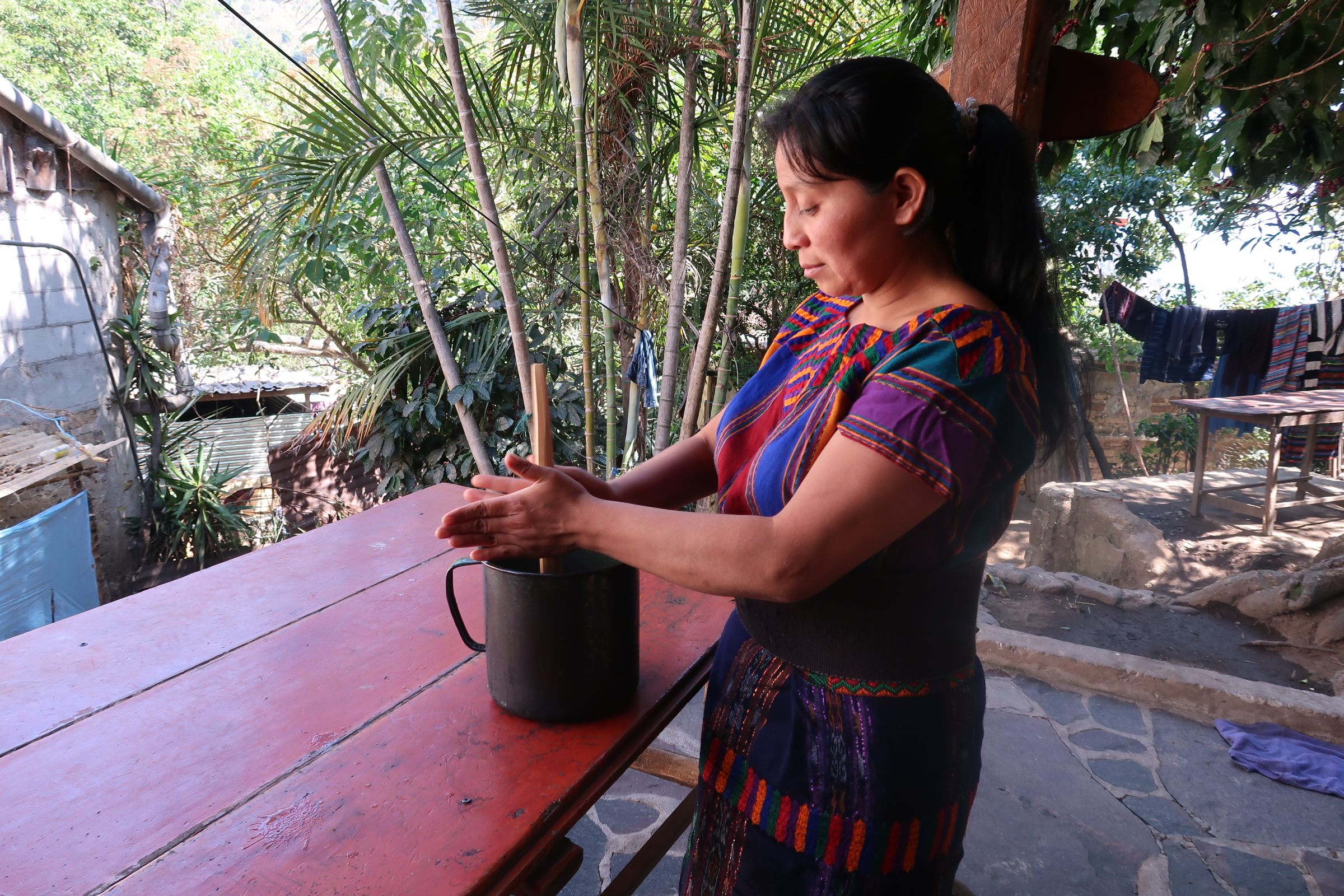 Maria generates froth in a hot cacao drink using a molinillo.