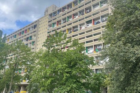 A colorful apartment building behind green trees shown at an angle.