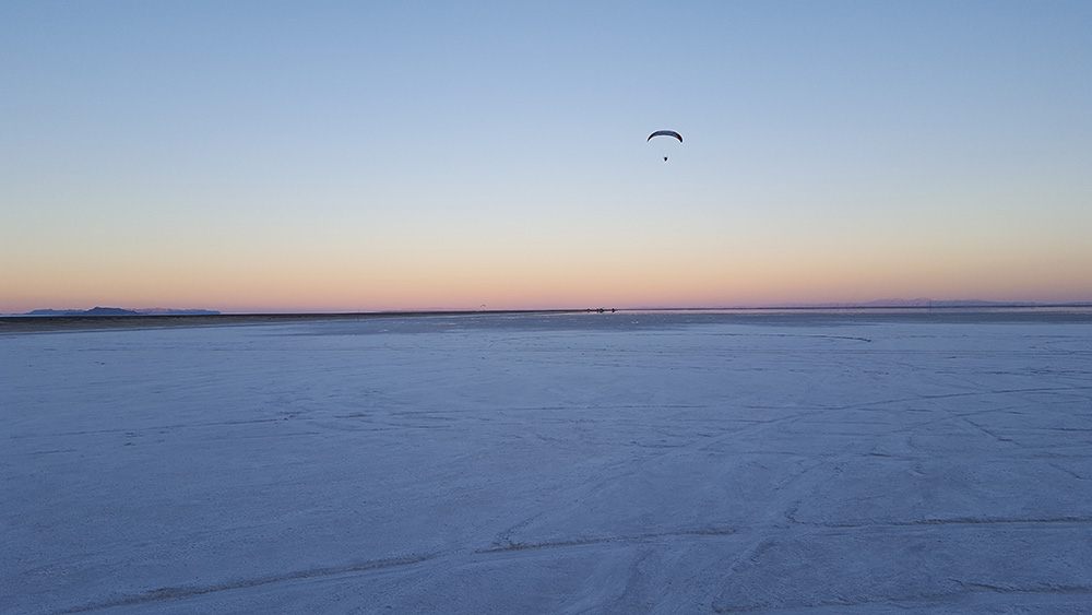 Paramotor pilot flying at sunset over the Bonneville Salt Flats in Utah.