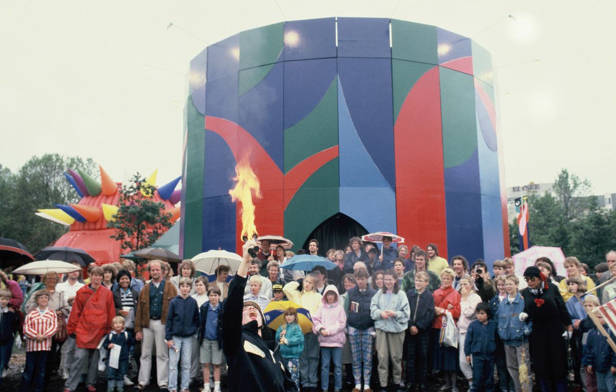 A fire eater performs in front of English artist David Hockney's geometric forest pavilion. Best known as a painter and photographer, Hockney was an important member of the 1960s Pop Art movement.