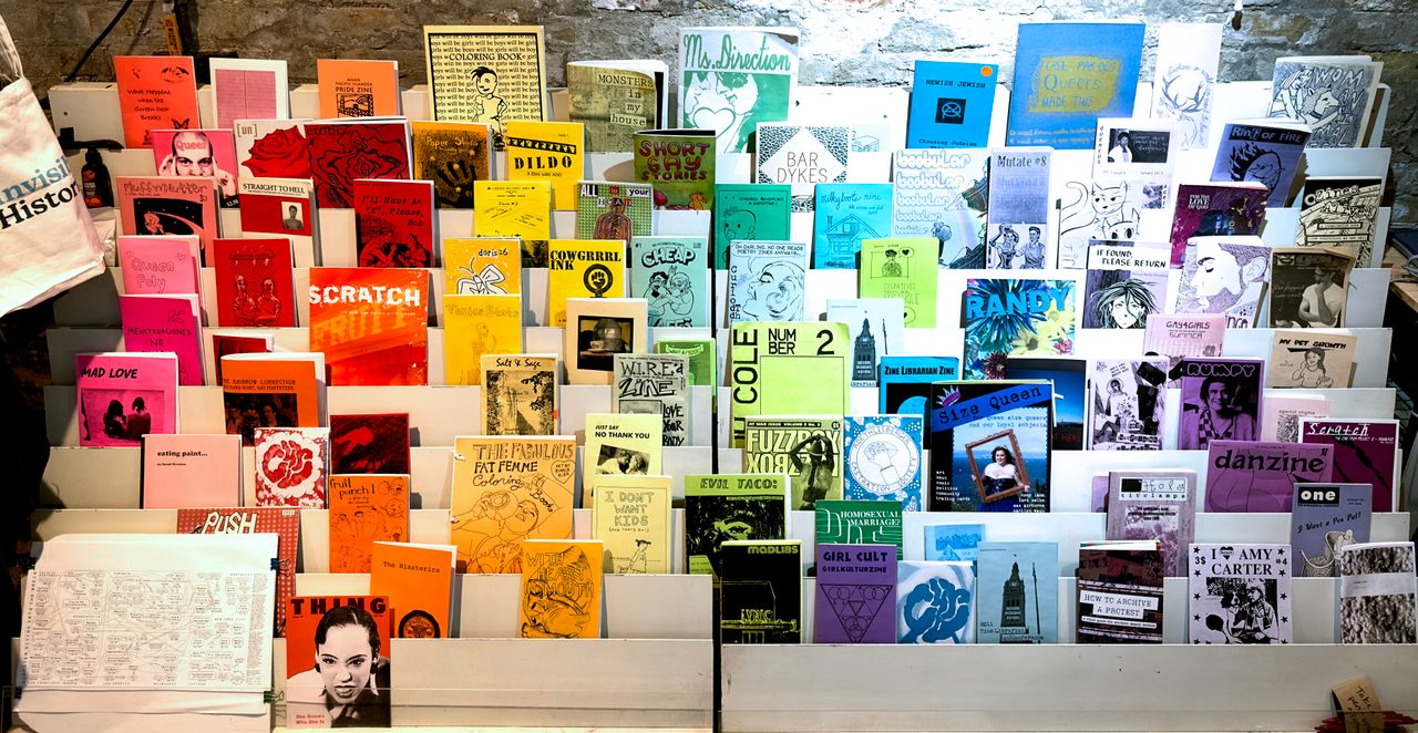 A rainbow display at the Queer Zine Archive Project, curated by QZAP interns Cole Lehto, Clementine Penner, and Kit Gordon in the summer of 2023.