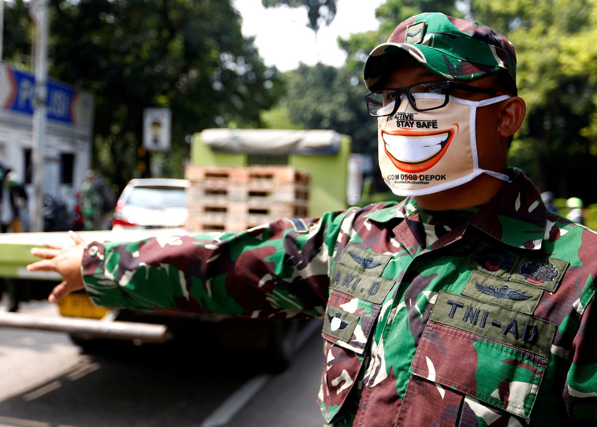 An Indonesian National Armed Forces member wears a face mask while directing traffic on the outskirts of Jakarta, April 15, 2020.