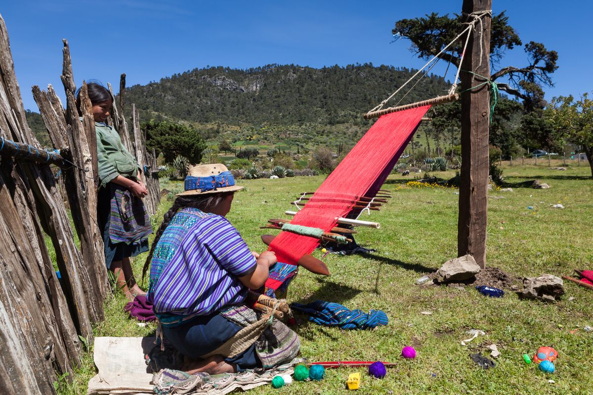 A weaver in Guatemala, near Huehuetenango, uses a loom attached to a pole.