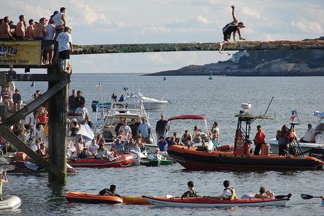 A man attempts to reach the flag during the courtesy round of the Greasy Pole