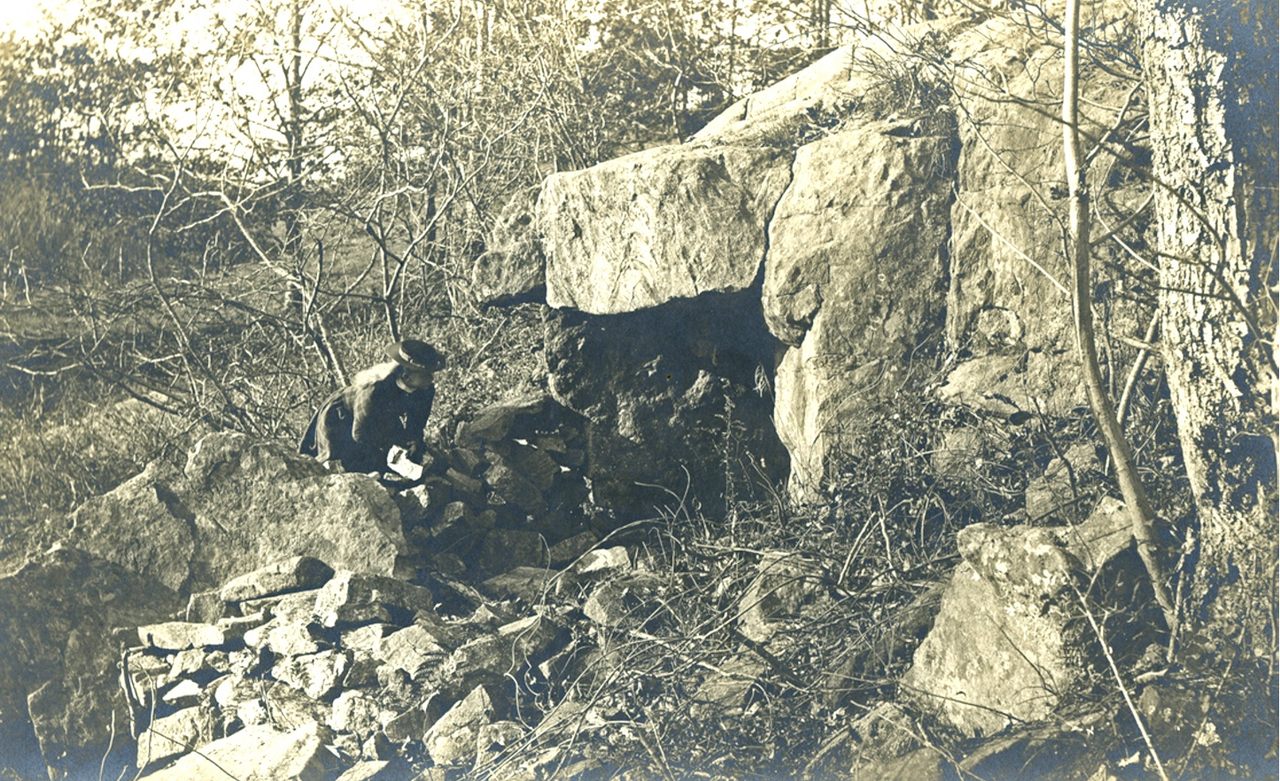 A woman peering into the cave of Sarah Bishop c. 1900.