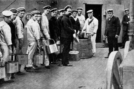 Sailors stand in line, eagerly awaiting their allotment of grog. 
