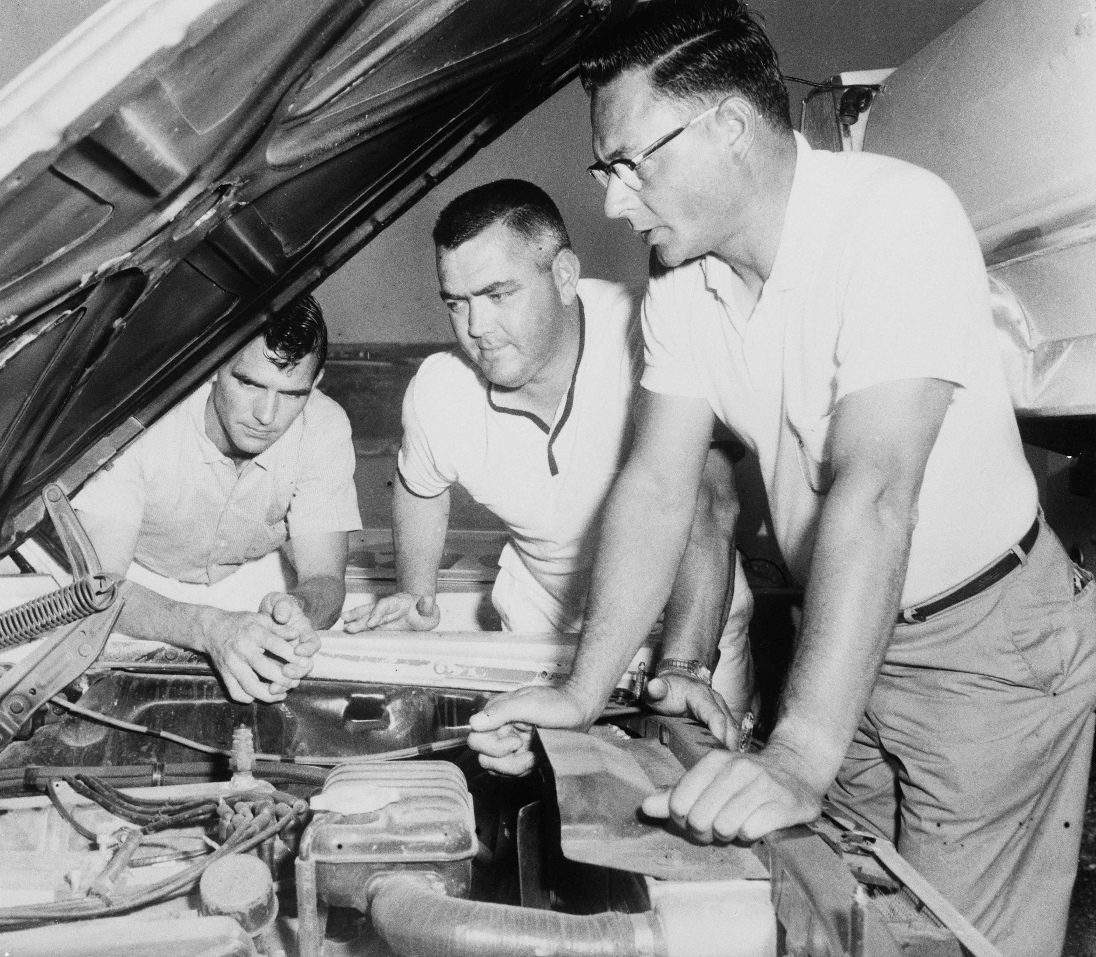 Mechanics help NASCAR driver Junior Johnson (center) check on his 1965 Ford before the start of the Watkins Glen Grand National stockcar race at Watkins Glen, New York.