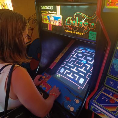 A girl with short brown hair plays a vintage arcade game.