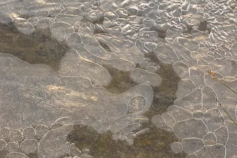 Watch These Mesmerizing Air Bubbles Flow Under Frozen Streams