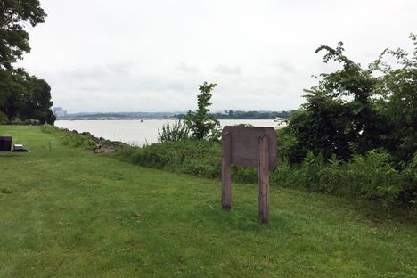 The sign is blocked by overgrown weeds.
