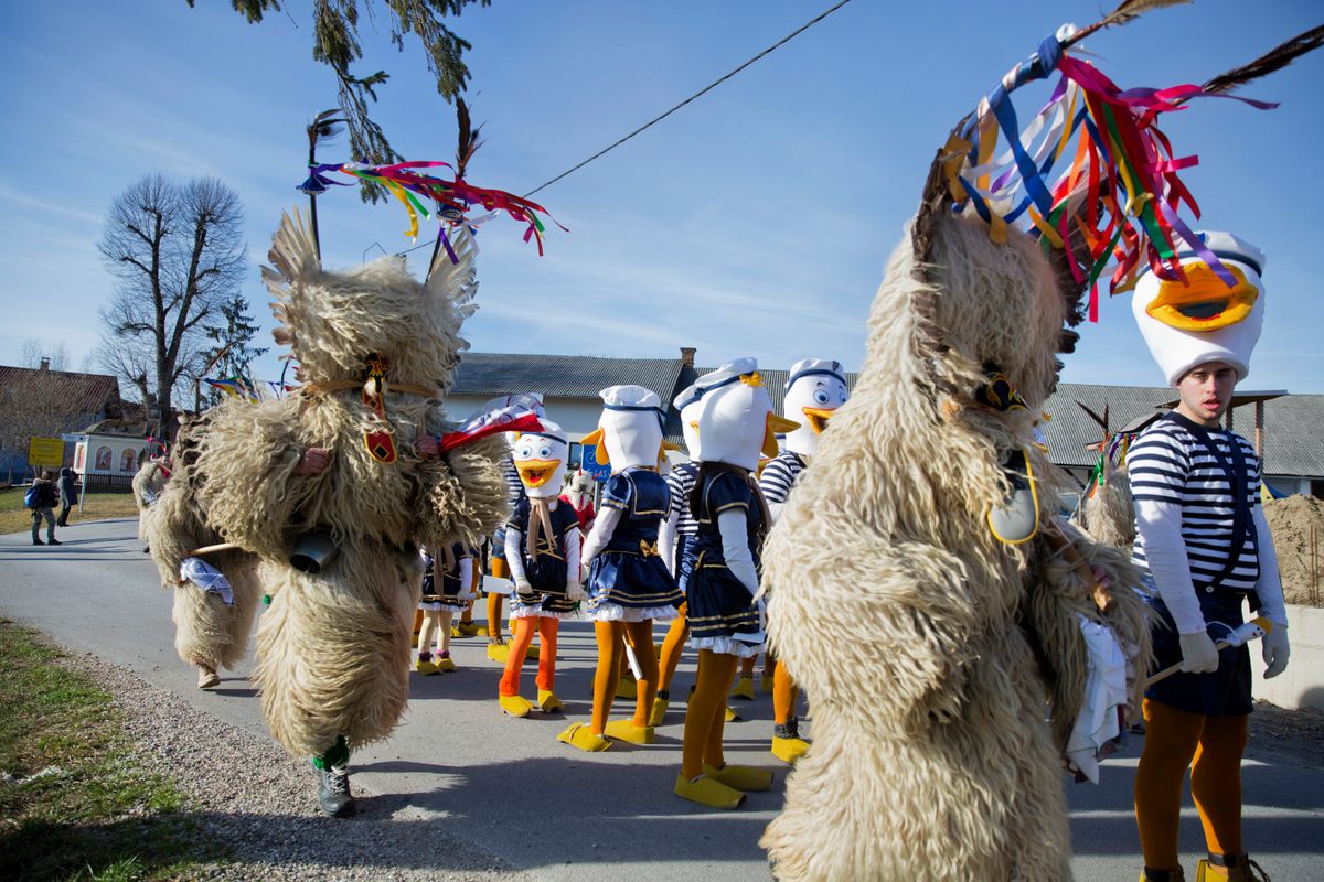 A group of Kurenti from the village of Zabovci passes a group wearing Donald Duck costumes before the village parade.