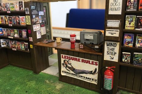 The counter at the mini store features a cash register, hand-written signs, and a fire extinguisher.
