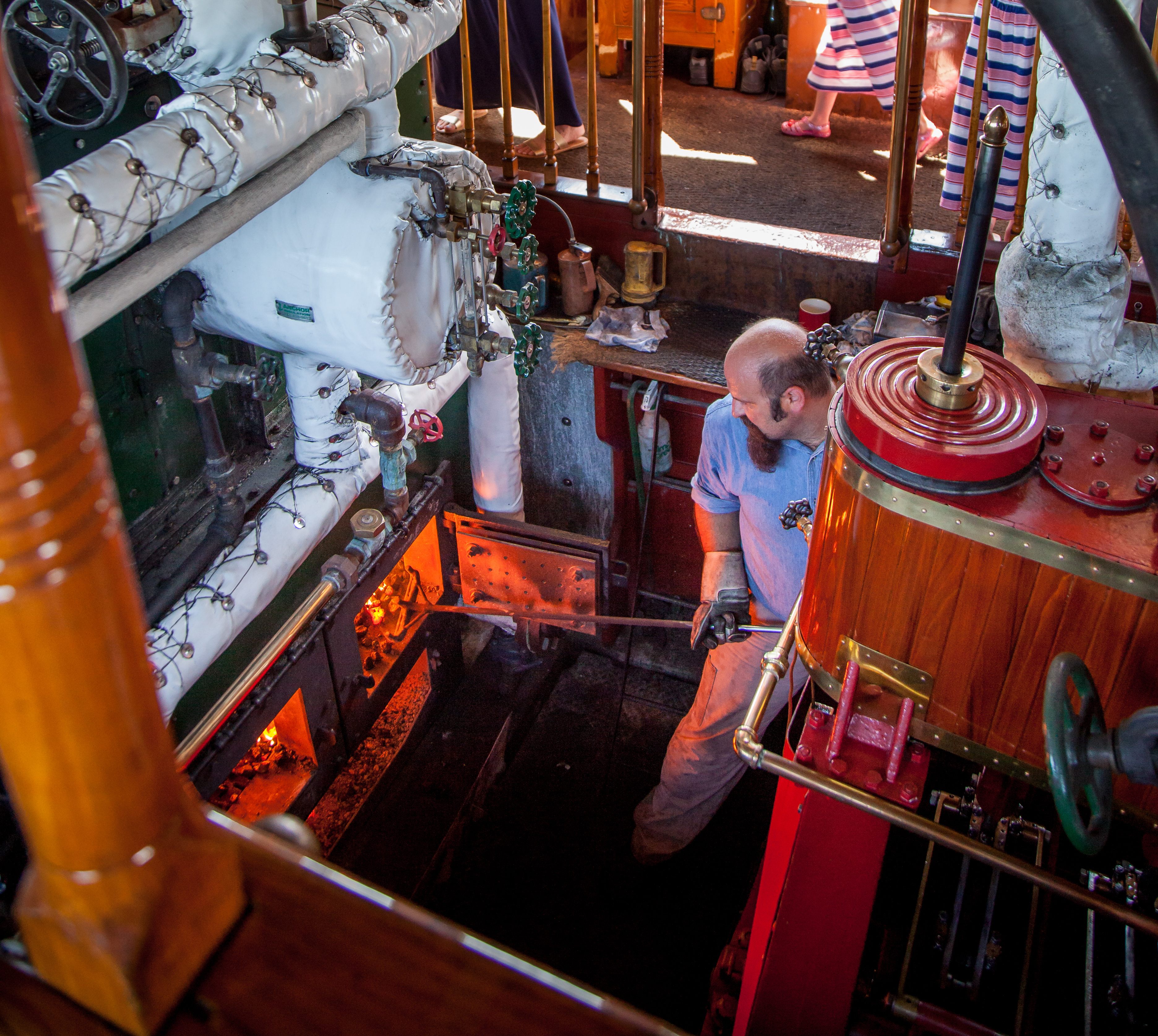 Jason Cabral, <em>Sabino</em>’s engineer, stokes coals in the firebox as the steamboat cruises the Mystic River.