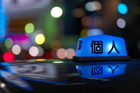 A bright blue neon sign of one of many unique symbols and shapes atop Tokyo's taxis.