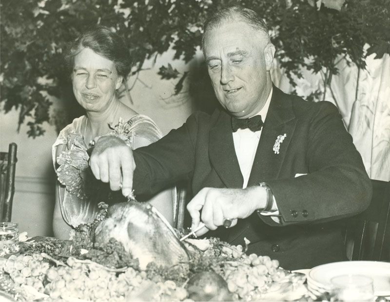 Roosevelt dismantles a turkey while Eleanor watches.