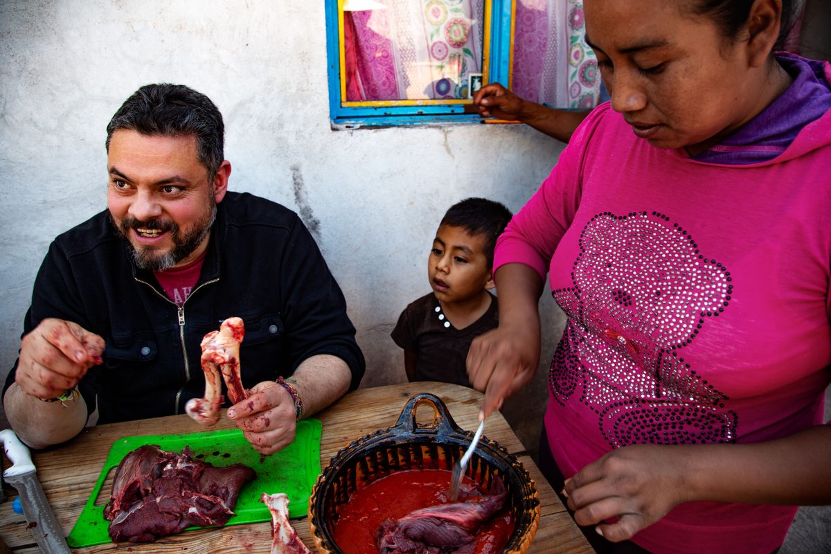 Chef Carlos Guillén and Jazmín Salas prepare the venison, while Salas's son Brayan watches on.