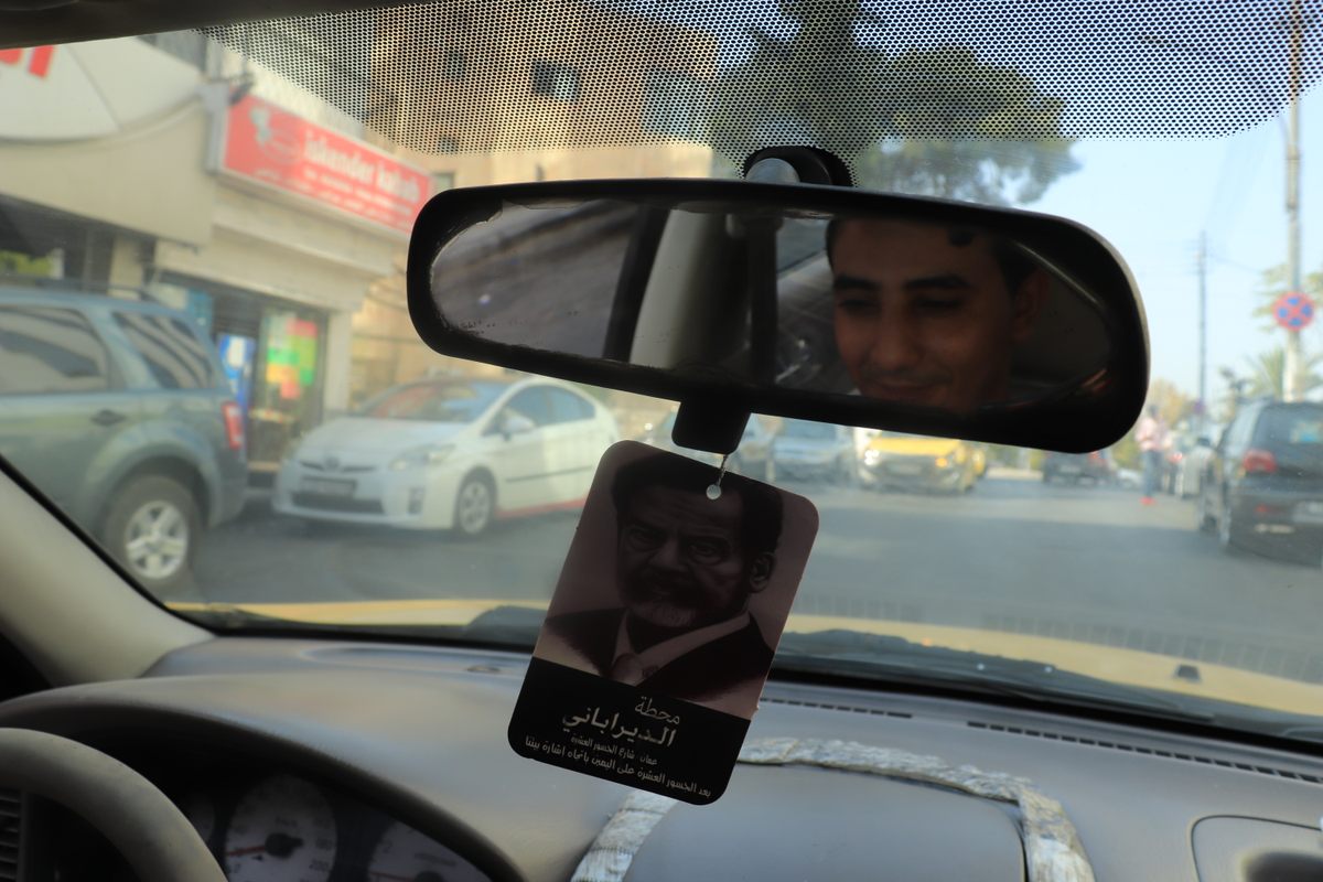 Saddam's image hangs from the rear-view mirror of Mustafa Khalid's taxi.