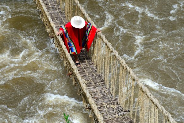 A local resident crosses the Apurímac River via a traditional rope bridge in Peru.