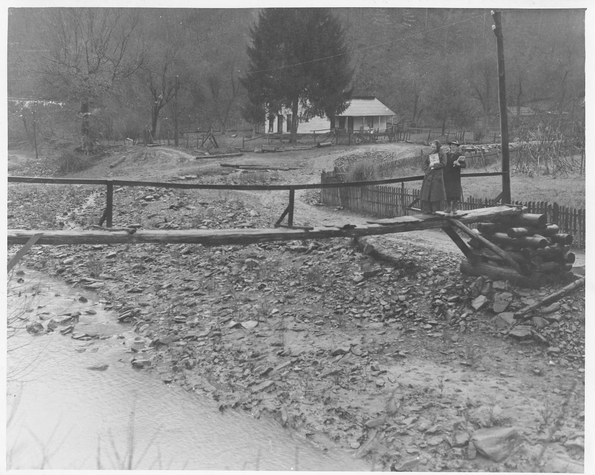 Pack horse librarians cross a log bridge to reach home used as a distribution center for a mountain community, year unknown.